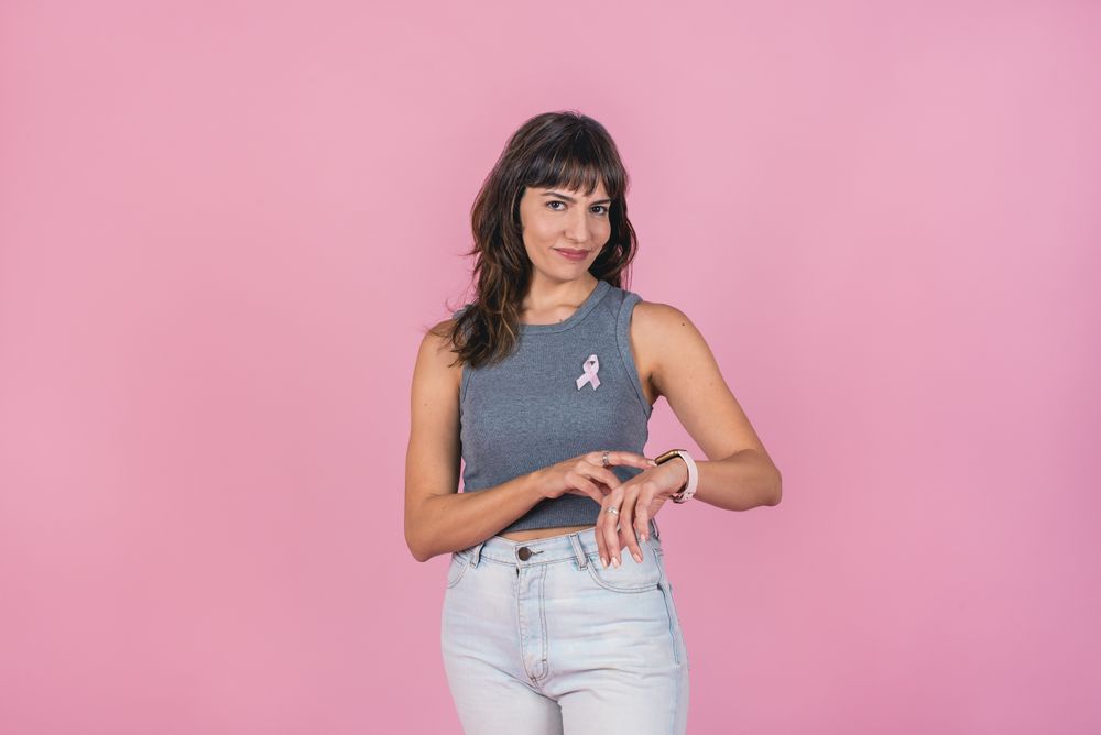 woman wearing a pink breast cancer ribbon showing her watch to raise awareness people to examine breast