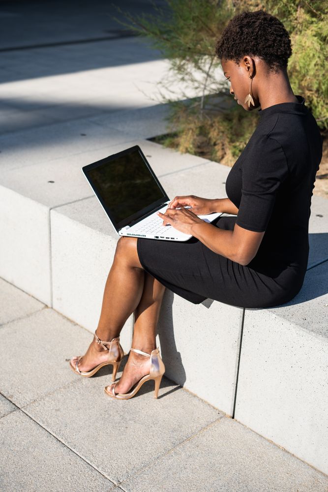Serious female surfing laptop near modern building
