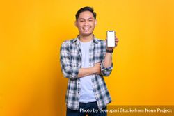 Happy Asian male showing blank screen of smart phone with arms crossed in studio shoot 0Wp165