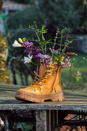 Bouquet of wildflowers in boot placed in countryside