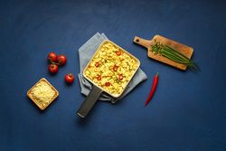 Scrambled eggs in a pan with cheese and chili pepper garnish