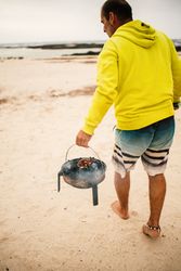 Tanned man cooking on camping stove beside parked mini van