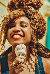 Close up of smiling Black female smiling with an ice cream cone in the sun, vertical