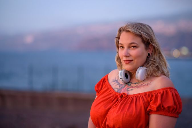 Smiling woman with tattoo and headphones on street