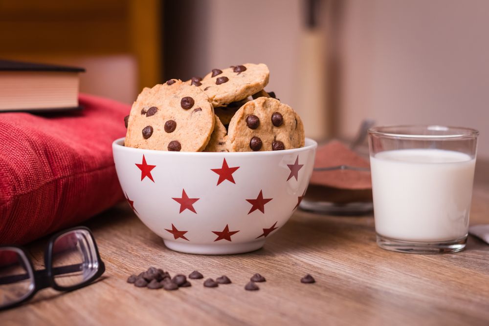 Chocolate chip cookies and milk on wood background