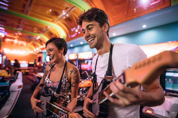 Couple at a gaming arcade playing musical guitar game