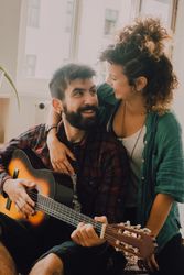 Cheerful couple playing guitar at home