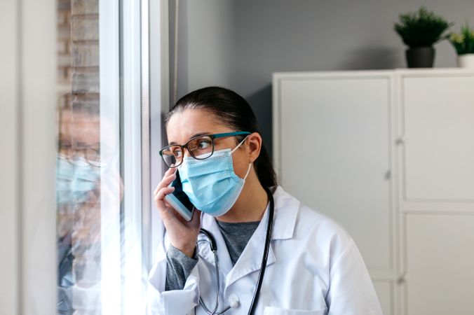 Female doctor talking on the cell phone looking out the window