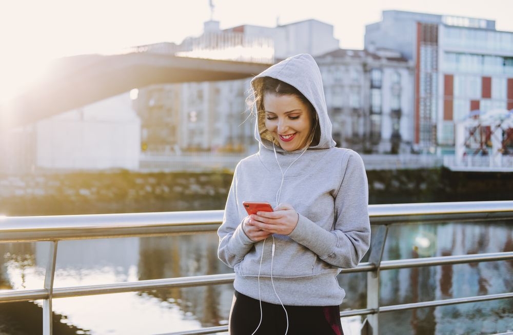 Woman with earphones wearing a hoodie on a embankment