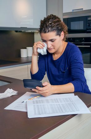 Woman with tissue, sad as she works through her bills