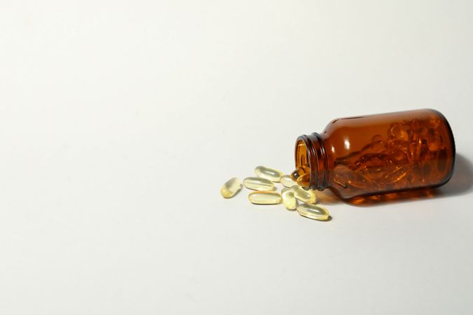 Brown bottle with omega pills on plain background