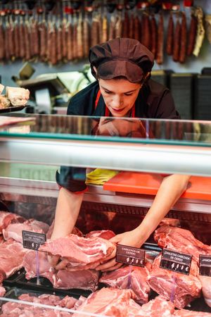 Female butcher taking meat from display