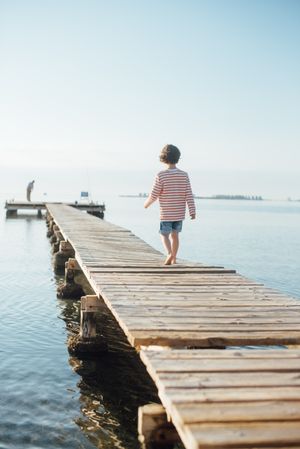 Lonely kid on pier in sunshine
