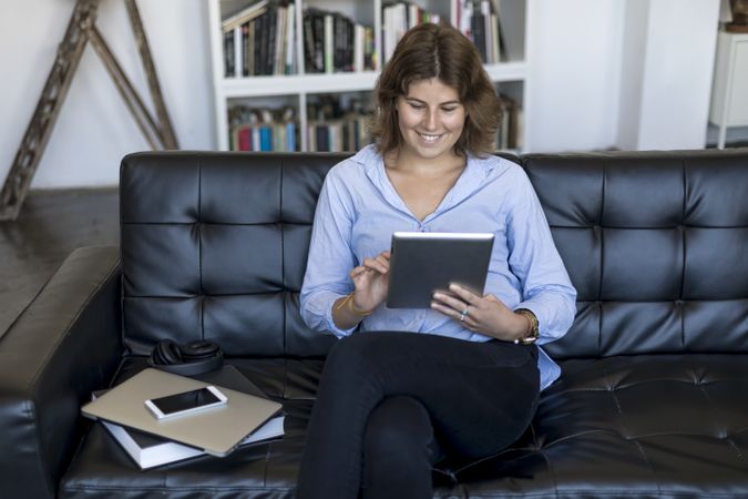 Female entrepreneur sitting on couch at home and using a digital tablet