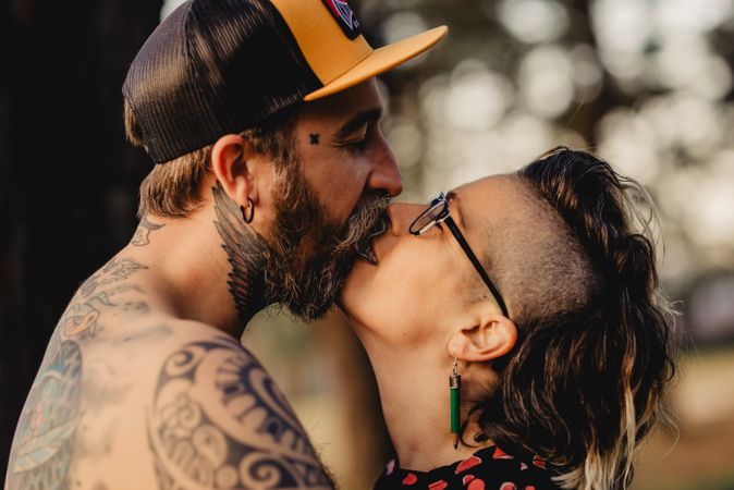 Young guy in tattoos hugging woman in forest