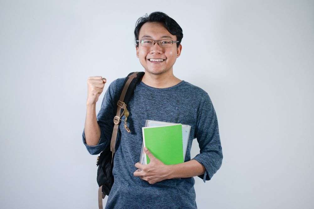 Asian student holding books and making strong gesture