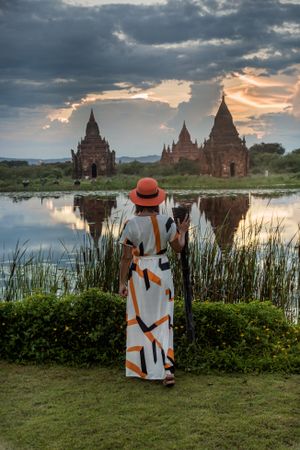 Woman standing at lakeside and enjoying view of Buddhist temples