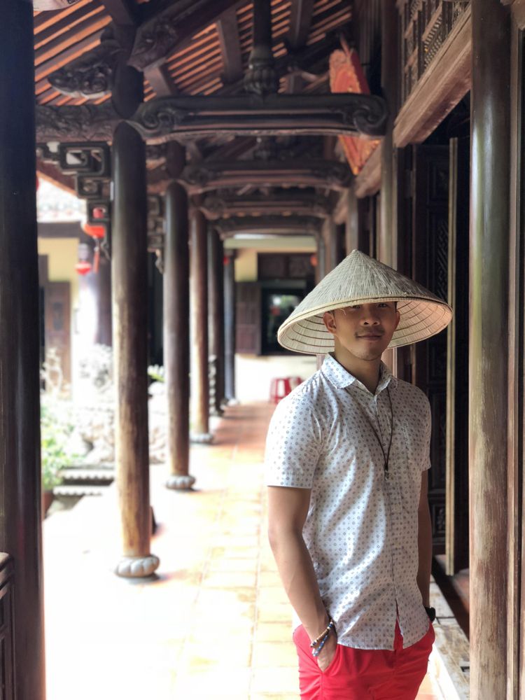 Man with conical hat standing at the hallway with both hands in his pockets near pillars