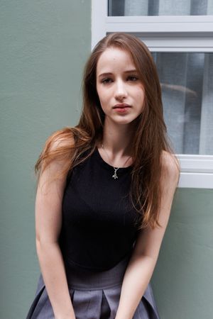 Portrait of young woman standing outside of window