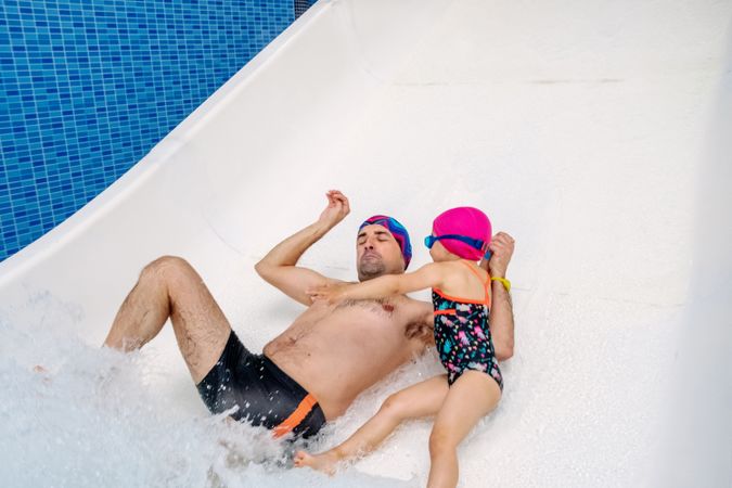 Father and daughter sliding in water park
