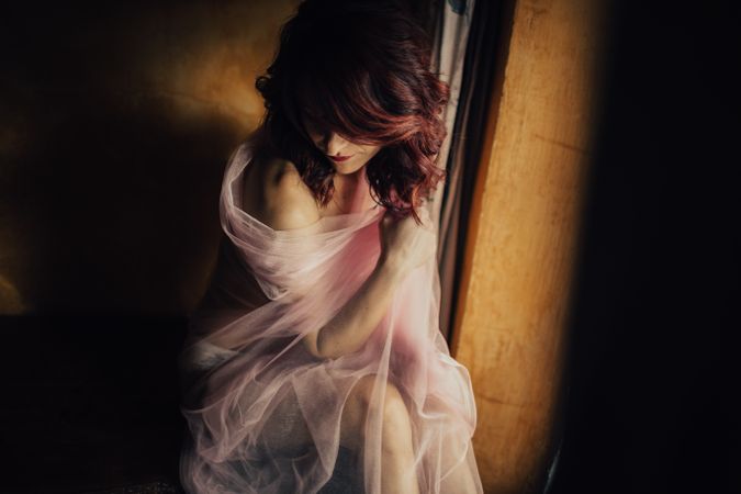 Sensual woman under veil near window