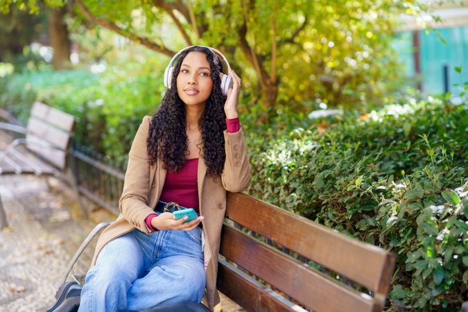 A Young Woman Delightfully Enjoying Music in a Relaxing Park Setting on a Pleasant Day