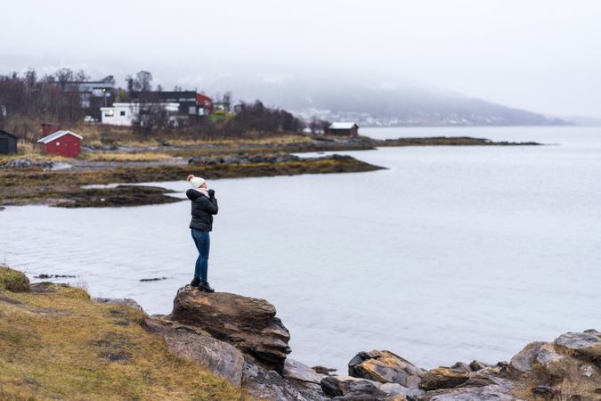 Female standing on stone cliff off coast
