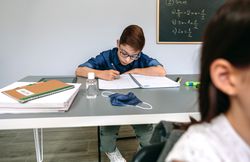 Boy writing in his notebook at school