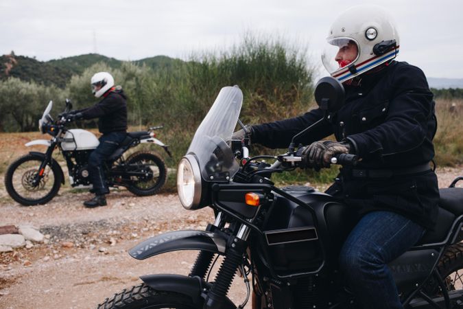 Two people preparing to ride motorcycle bikes