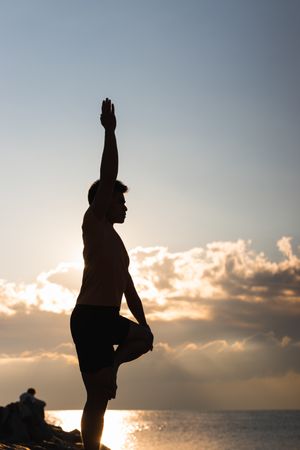 Man practicing yoga asana at sunset