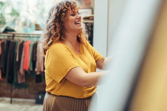 Cheerful woman choosing new clothes in boutique store