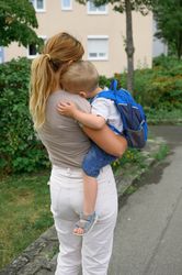 Unrecognizable mother standing and carrying anonymous kid in hands