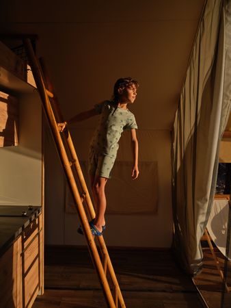 Boy in sleepwear standing on wooden ladder