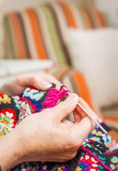 Hands of woman knitting a vintage wool quilt
