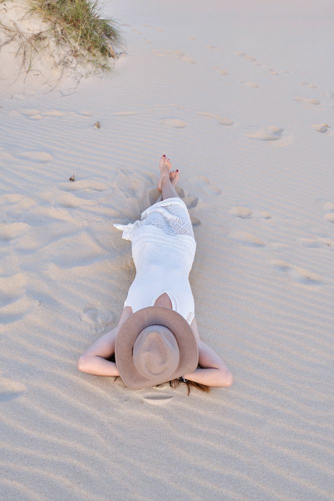 Woman in white dress relaxing on sand