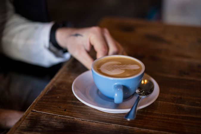 Man with cappuccino on wooden table