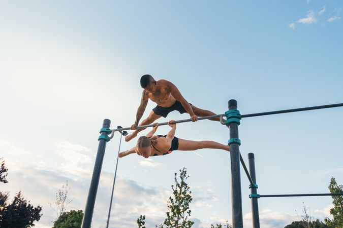 couple training together in a calisthenics park, doing back lever and straddle planche.