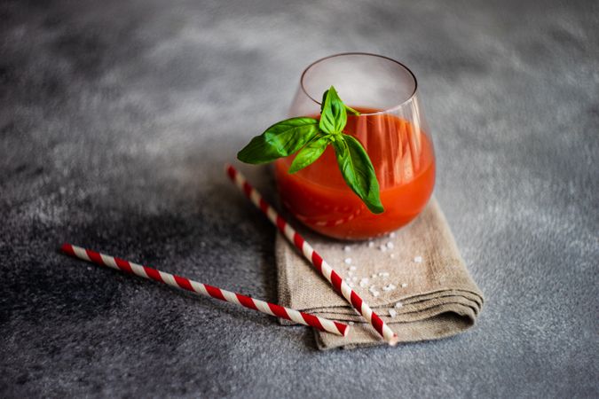 Fresh tomato juice with straws and basil garnish