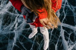 Woman in skates standing on ice and using phone
