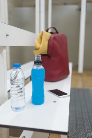 Empty shower room with backpack and drinks on bench, vertical composition