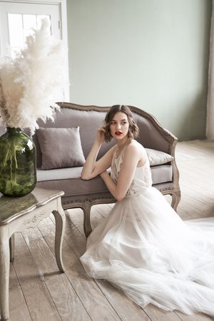 woman with red lips in white dress looking away while sitting on floor beside sofa