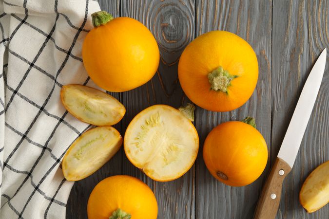 Round zucchini, knife and napkin on wooden background