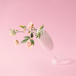 Champagne glass with spring flowers against pink background