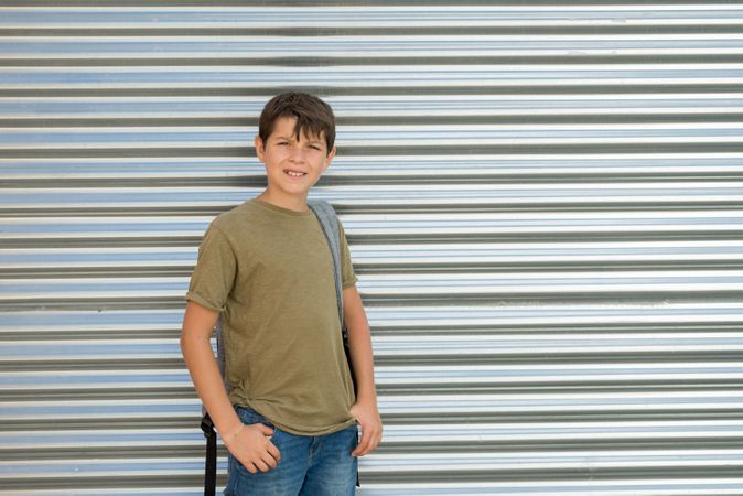 Smiling teenage male in back pack standing outside of street shutter