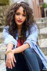 Female with curly hair sitting on cement stairs outside