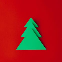 Minimal paper art style folded paper Christmas tree on red background