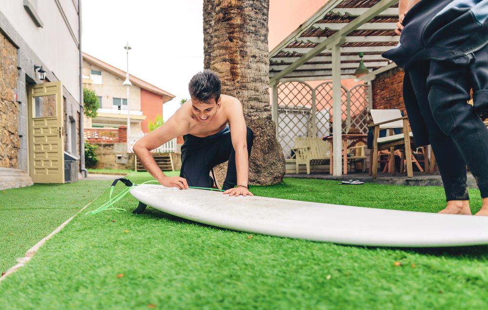 Male surfer in wetsuit waxing surfboard