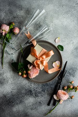 Pink flowers and gift with ribbon on plates with grey background