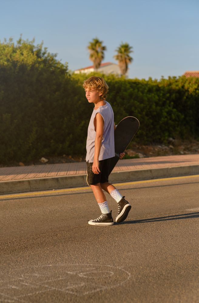 Calm skater walking with skateboard in sunset