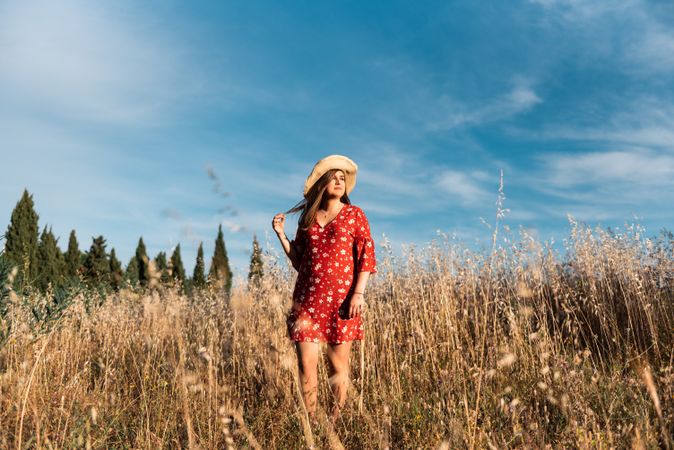 Happy dreamy woman standing among high grass